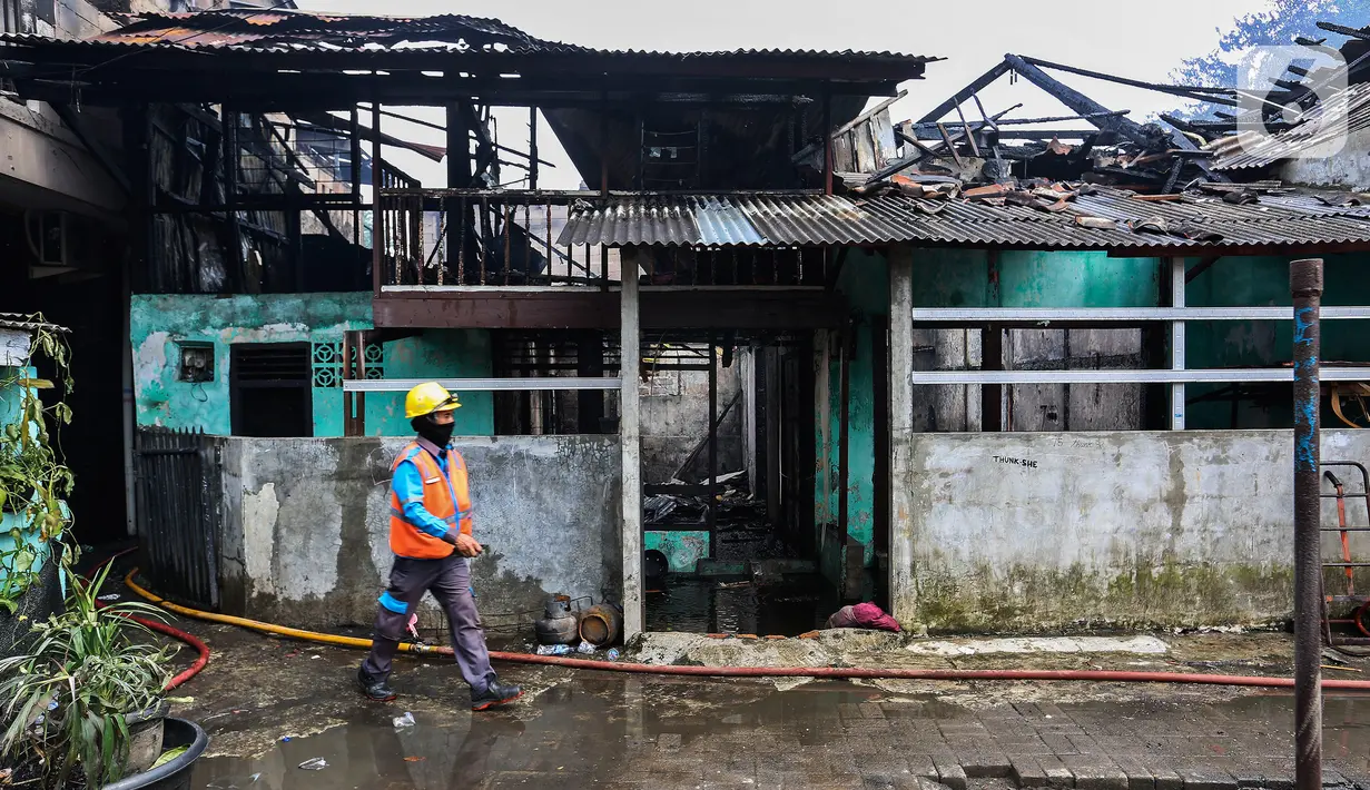 Petugas pemadam kebakaran melintas di depan salah satu rumah warga yang terbakar di Jalan Masjid Alhuda atau depan Stasiun Kebayoran Lama RT 05/01, Jakarta Selatan, Selasa (24/5/2022). Petugas pun mengerahkan 27 unit mobil pemadam kebakaran dari Sudin Damkar Jakarta Selatan ke lokasi kejadian. (Liputan6.com/Johan Tallo)