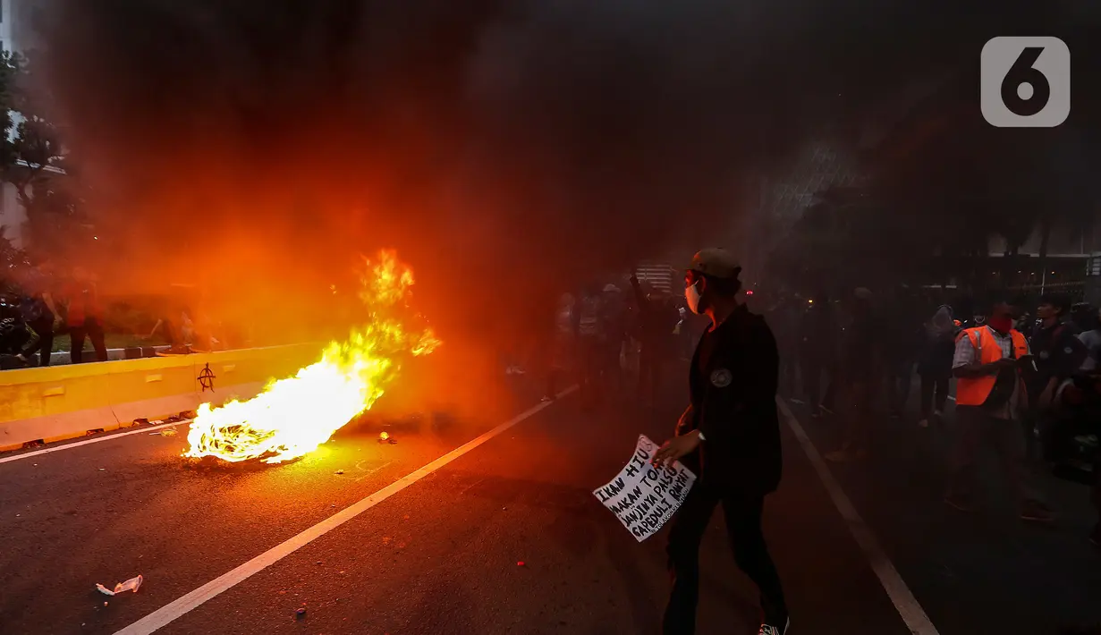 Massa aksi demo menolak Omnibus Law UU Cipta Kerja membakar ban bekas di Jalan Medan Merdeka Barat, Jakarta Pusat, Selasa (20/10/2020). Gelombang protes tolak UU Cipta Kerja belum surut sejak disahkan pada 5 Oktober lalu. (Liputan6.com/Johan Tallo)