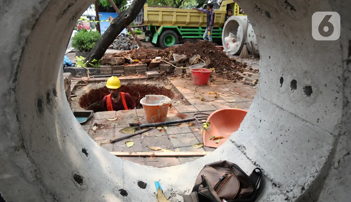 Pekerja saat membuat lubang untuk sumur rasapan di Jalan Kebon Jeruk, Jakarta Barat, Jumat (15/10/2021). Hingga saat ini, Pemprov DKI Jakarta sudah membuat sumur resapan di 6.233 titik. (Liputan6.com/Johan Tallo)