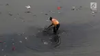 Petugas membersihkan sampah yang mengendap di Kanal Banjir Timur, Jakarta, Selasa (19/9). Diperkirakan sungai itu tercemar limbah sehingga airnya berwarna hitam pekat dan mengeluarkan bau tak sedap serta berbusa. (Liputan6.com/Immanuel Antonius)