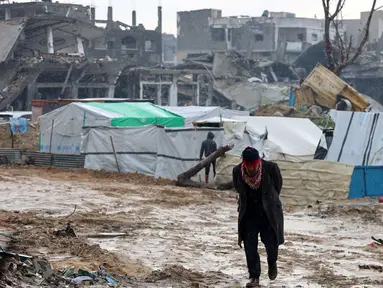 Seorang pria Palestina berjalan di depan tenda-tenda yang didirikan di tengah kehancuran di Beit Hanoun, Jalur Gaza utara pada 12 Februari 2025. (Omar AL-QATTAA/AFP)