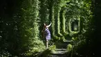 Seorang gadis berjalan di sepanjang bekas rel kereta api atau disebut 'Tunnel of Love' yang dikelilingi pohon dekat desa Ukraina Klevan, Rivno, (6/8). Terowongan cinta yang panjangnya sekitar lima km adalah fenomena botani. (AFP Photo/Sergei Supinsky)