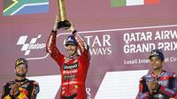 Pembalap Ducati Lenovo, Francesco Bagnaia, mengangkat trofi juara MotoGP Qatar setelah mengungguli Brad Binder dan Jorge Martin di Lusail International Circuit, Senin (11/3/2024) dini hari WIB. (KARIM JAAFAR / AFP)