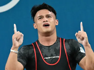 Rizki Juniansyah dari Indonesia melakukan selebrasi setelah memecahkan rekor di cabang olahraga angkat besi kelas 73kg putra selama Olimpiade Paris 2024 di South Paris Arena di Paris, pada 8 Agustus 2024 atau Jumat (9/8/2024) dini hari WIB. (Miguel MEDINA/AFP)