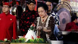 Ketua Umum PDIP Megawati Soekarnoputri memotong tumpeng pada pagelaran wayang kulit dalam rangka HUT PDIP ke-45 di Tugu Proklamasi, Jakarta, Sabtu Malam (27/1). Megawati juga membagikan 45 sepeda gunung kepada penonton.(Liputan6.com/Johan Tallo)