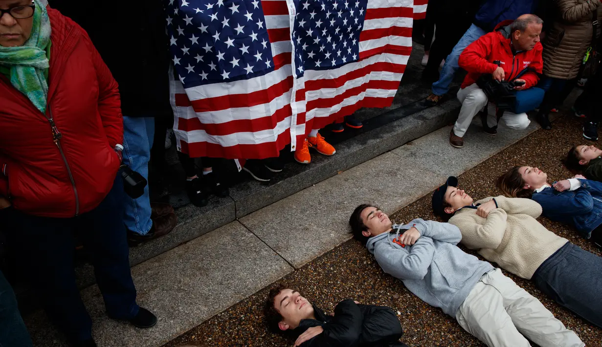 Pengunjuk rasa yang didominasi para siswa SMA berbaring di jalan depan Gedung Putih, Washington, Senin (19/2). Mereka berbaring selama tiga menit tanpa peduli kedinginan atau kebasahan. (AP Photo/Evan Vucci)
