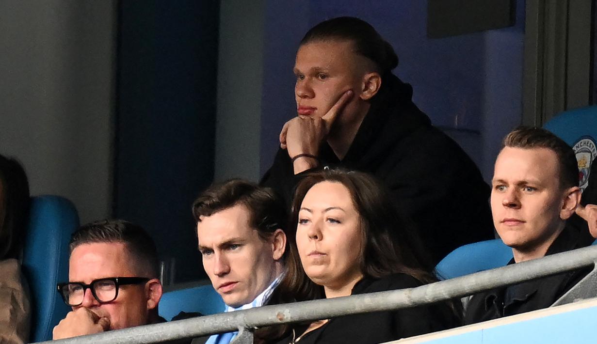 Striker Manchester City, Erling Haaland (atas) duduk di tribun saat menghadapi Liverpool pada laga Liga Inggris 2022/2023 di Etihad Stadium, Manchester (1/4/2023). Sementara pada pertemuan kedua di Etihad Stadium pada pekan ke-29, Erling Haaland kembali gagal menyumbang gol dalam kemenangan 4-1 atas Liverpool karena tak bermain sama sekali akibat cedera. (AFP/Paul Ellis)