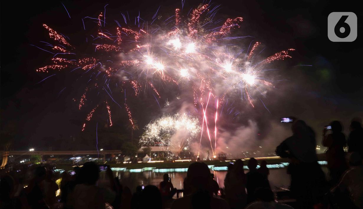 Warga menyaksikan pesta kembang api saat perayaan malam puncak Tahun Baru 2023 di Danau Archipelago, Taman Mini Indonesia Indah (TMII), Jakarta, Minggu (1/1/2023). Perayaan malam puncak Tahun Baru 2023 yang digelar Pemerintah Provinsi DKI Jakarta di TMII menghadirkan pesta kembang api yang berlangsung selama 15 menit. (Liputan6.com/Herman Zakharia)