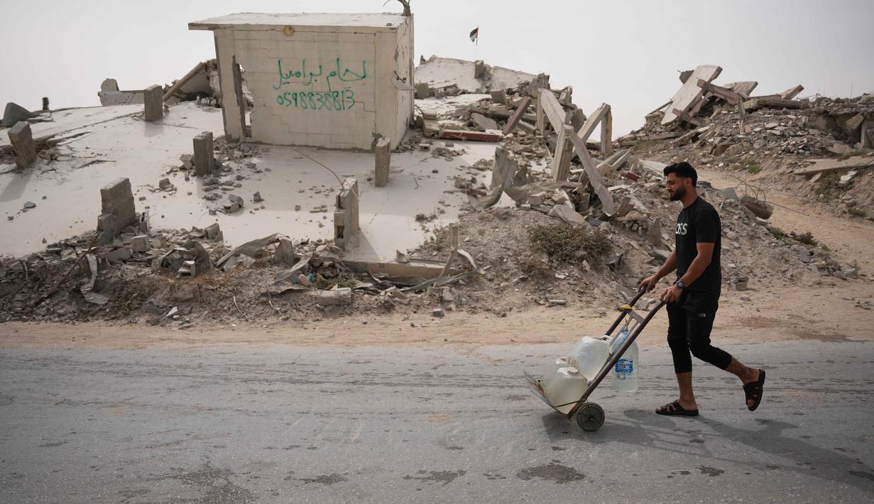 UNICEF mencatat 90 persen penduduk Gaza tidak memiliki akses aman terhadap air minum, sementara 96 persen air tanah telah tercemar dan tidak layak digunakan. Tampak dalam foto, seorang pria Palestina membawa wadah air di Kota Gaza, Selasa 12 Mei 2026. (AP Photo/Abdel Kareem Hana)