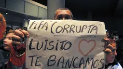 Sambil menanti kedatangan Luis Suarez di Bandara Montevideo, Carrasco, (26/6/2014), salah satu warga Uruguay membentangkan tulisan berbunyi "FIFA korup - Luis, kita mencintai dan mendukungmu". (REUTERS/Carlos Pazos)
