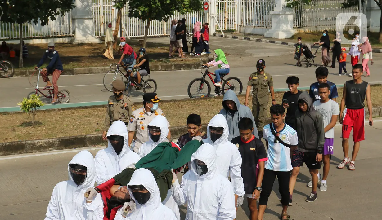 Petugas Satpol PP Kabupaten Bogor yang mengenakan pakaian hazmat menggotong warga pelanggar PSBB di kawasan Stadion Pakansari, Kabupaten Bogor, Jawa Barat, Minggu (6/9/2020). Pemkab Bogor menerapkan sanksi denda Rp 100 ribu serta sanksi sosial bagi pelanggar PSBB. (Liputan6.com/Herman Zakharia)