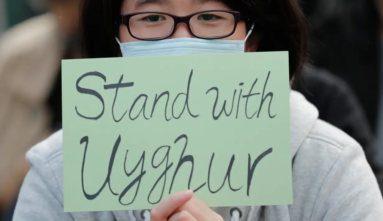 Seorang demonstran memegang kertas bertuliskan dukungan untuk Uighur dan perjuangan mereka terhadap hak azasi manusia di Hong Kong, Minggu (22/12/2019). Demonstran memprotes kebijakan China terkait minoritas Uighur. (AP Photo/Lee Jin-man)