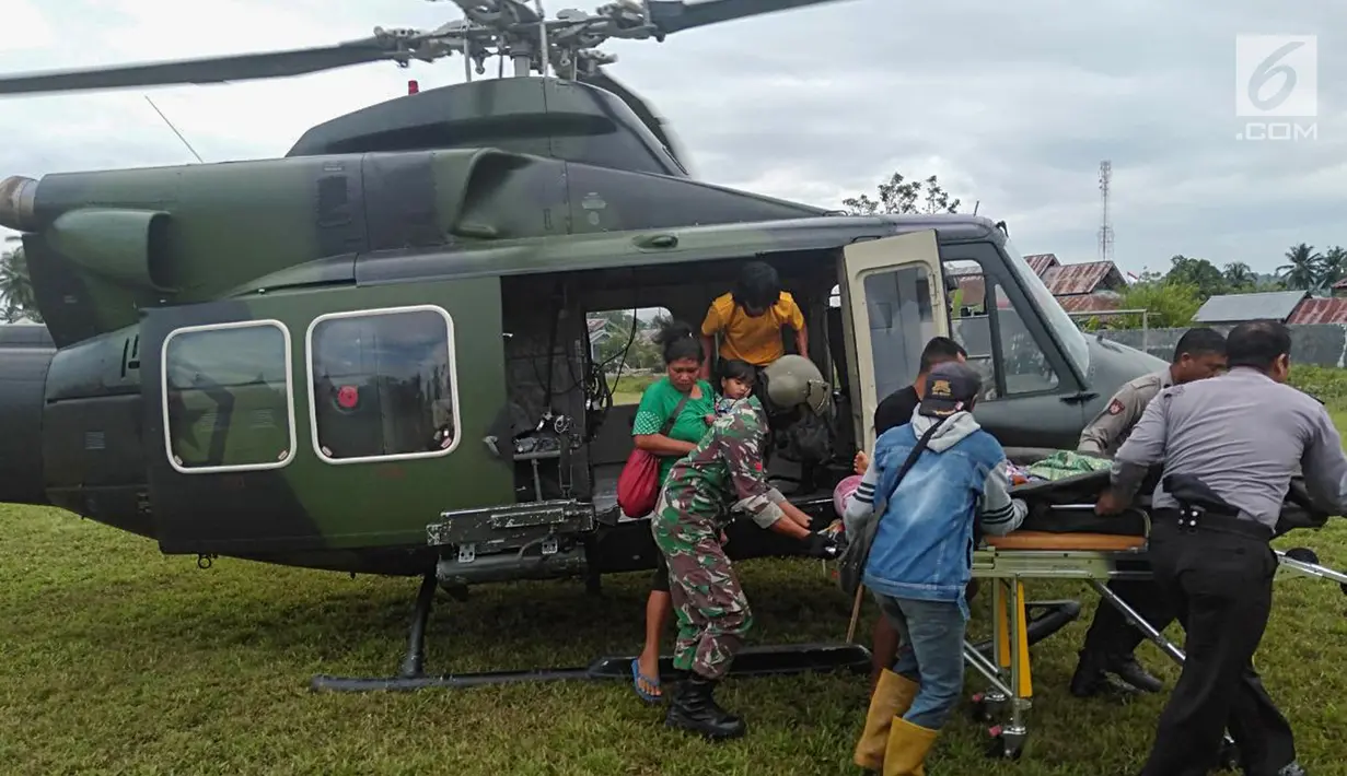 TNI-Polri dan warga mengevakuasi Heriani yang akan melahirkan saat tiba menggunakan helikopter di Dusun Air Teh, Sulawesi Tengah, Sabtu (27/7/2019). Mereka membawa ibu yang akan melahirkan menuju Puskesmas Sausu untuk ditangani petugas kesehatan setempat. (Liputan6.com/HO/Satgas TNI-Tinombala)