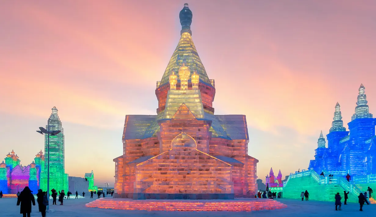 Orang-orang mengunjungi Harbin Ice Snow World di Harbin, provinsi Heilongjiang, China, 24 Desember 2018. Di malam hari, balok es yang membentuk patung-patung ini akan disinari dengan lampu warna-warni. (STR / AFP)