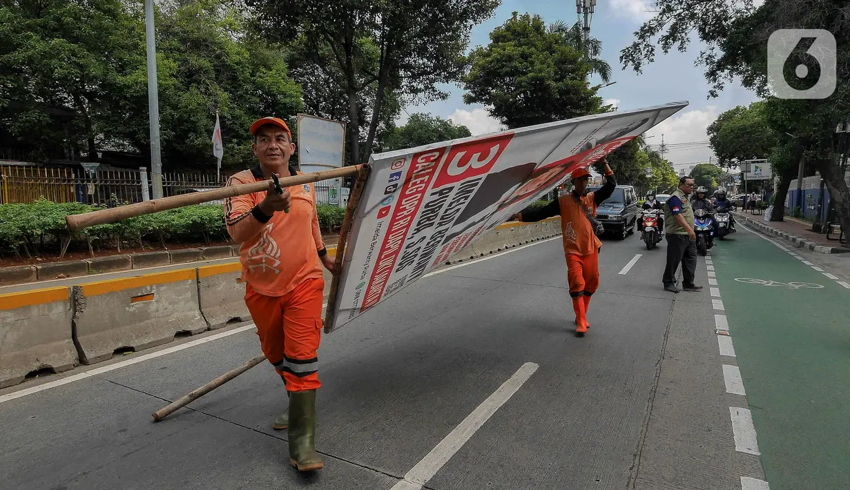 Petugas Penanganan Prasarana dan Sarana Umum (PPSU) menurunkan Alat Peraga Kampanye (APK) yang masih terpasang di kawasan Jati Padang, Jakarta, Minggu (11/2/2024). (Liputan6.com/Herman Zakharia)
