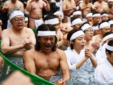 Orang-orang percaya Shinto dari Kuil Teppozu Inari mandi dengan air dingin untuk menyucikan jiwa dan tubuh mereka selama ritual Tahun Baru di Tokyo, Minggu (12/1/2020). Sekitar 100 orang percaya Shinto ambil bagian dalam ritual tahunan tersebut. (AFP/Charly Triballeau)