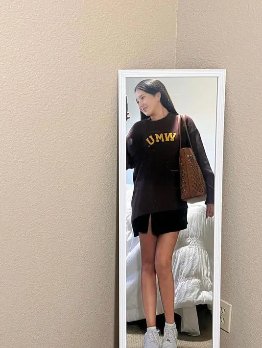 Sweater tersebut dipadukan dengan rok mini warna hitam, sneakers putih, dan tote bag coklat. (Instagram/bebytsabina).