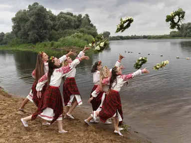 Wanita Belarusia yang mengenakan kostum nasional melemparkan karangan bunga ke Sungai Berezina pada Hari Ivan Kupala di Desa Parichi, sekitar 200 km (125 mil) selatan Parichi, Belarus, 6 Juli 2022. Hari Ivan Kupala merupakan sebuah perayaan malam kuno yang menandai Titik Balik Matahari Musim Panas, malam terpendek tahun ini. (AP Photo/Viktor Drachev)
