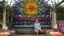 Pengunjung duduk di bawah rangkaian bunga yang dipamerkan pada RHS (Royal Horticultural Society) Chelsea Flower Show, London, Senin (215/). Ini adalah pameran bunga yang paling terkenal di Inggris, dan mungkin di dunia. (Daniel LEAL-OLIVAS/AFP)