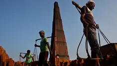 Para pekerja India membawa batu bata di pundak mereka di pabrik pembuatan batu bata di pinggiran Gauhati, India (22/11). Mereka menghasilkan 120 Rupee (kurang dari 2 Dolar) per hari. (AP Photo/Anupam Nath)