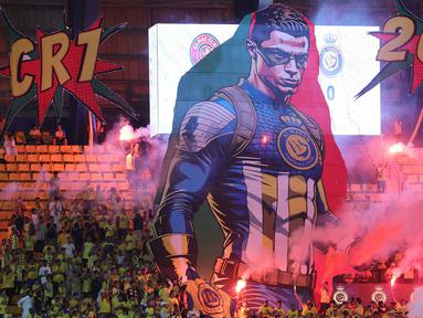 Cristiano Ronaldo kembali menjadi penentu kemenangan Al Nassr saat menghadapi Damac pada laga pekan ke-10 Liga Arab Saudi 2023/2024 yang berlangsung di King Saud University Stadium, Riyadh, Sabtu (21/10/2023) malam WIB. Sempat tertinggal lewat gol Georges Nkoudou pada menit ke-45, Al Nassr melakukan comeback sempurna dengan mencetak dua gol di babak kedua untuk membalikkan keadaan 2-1. Dua gol Al Nassr dicetak lewat dua sepakan bebas pemain andalannya, Anderson Talisca pada menit ke-52 dan Cristiano Ronaldo empat menit kemudian. Dalam laga tersebut para pendukung Al Nassr membentangkan spanduk raksasa bergambar superhero Captain America yang bagian kepalanya diganti dengan wajah CR-7 sebagai apresiasi capaian 200 caps bersama Timnas Portugal. (AFP/Fayez Nureldine)