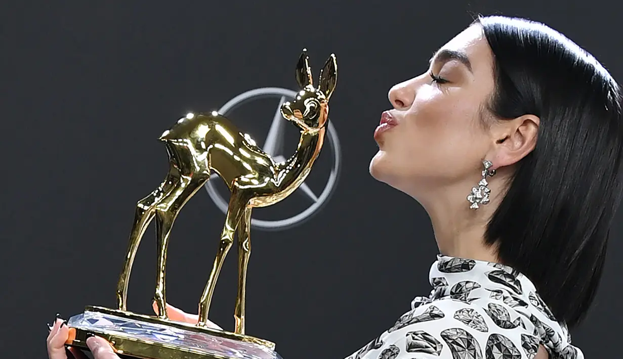 Penyanyi Inggris Dua Lipa  mencium Penghargaan Bambi Awards ke-70 yang ia raih di Potsdamer Platz di Berlin (16/11). Dua Lipa meraih penghargaan kategori Music International di acara tersebut. (AFP Photo/Jens Kalaene)