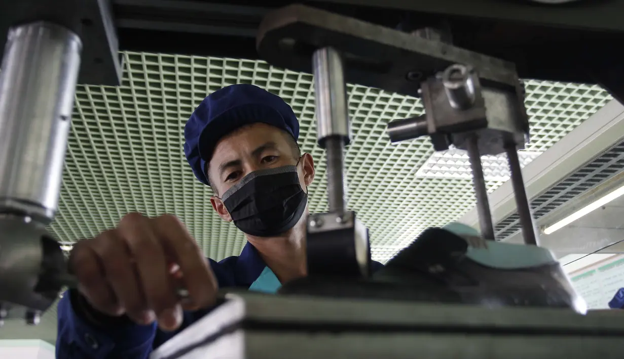 Seorang pekerja yang memakai masker saat bekerja di Pabrik Sepatu Kulit Wonsan, tempat memproduksi sepatu kulit buatan tangan di Wonsan, Provinsi Kangwon, Korea Utara pada 28 Oktober 2020. (AP Photo/Jon Chol Jin)