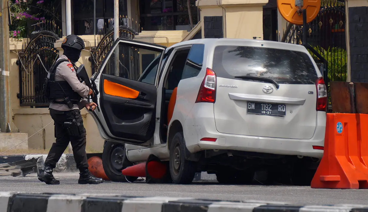 Seorang petugas memeriksa sebuah minubus yang digunakan dalam serangan di Mapolda Riau Rabu (16/5). (AP Photo/Akbari)