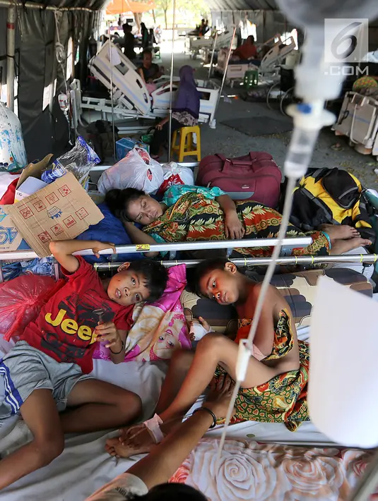 Dua pasien anak korban gempa bumi dan tsunami Palu dirawat di halaman Rumah Sakit Undata, Palu, Sulawesi Tengah, Kamis (4/10). Mereka dirawat menggunakan tenda bantuan dengan fasilitas seadanya. (Liputan6.com/Fery Pradolo)