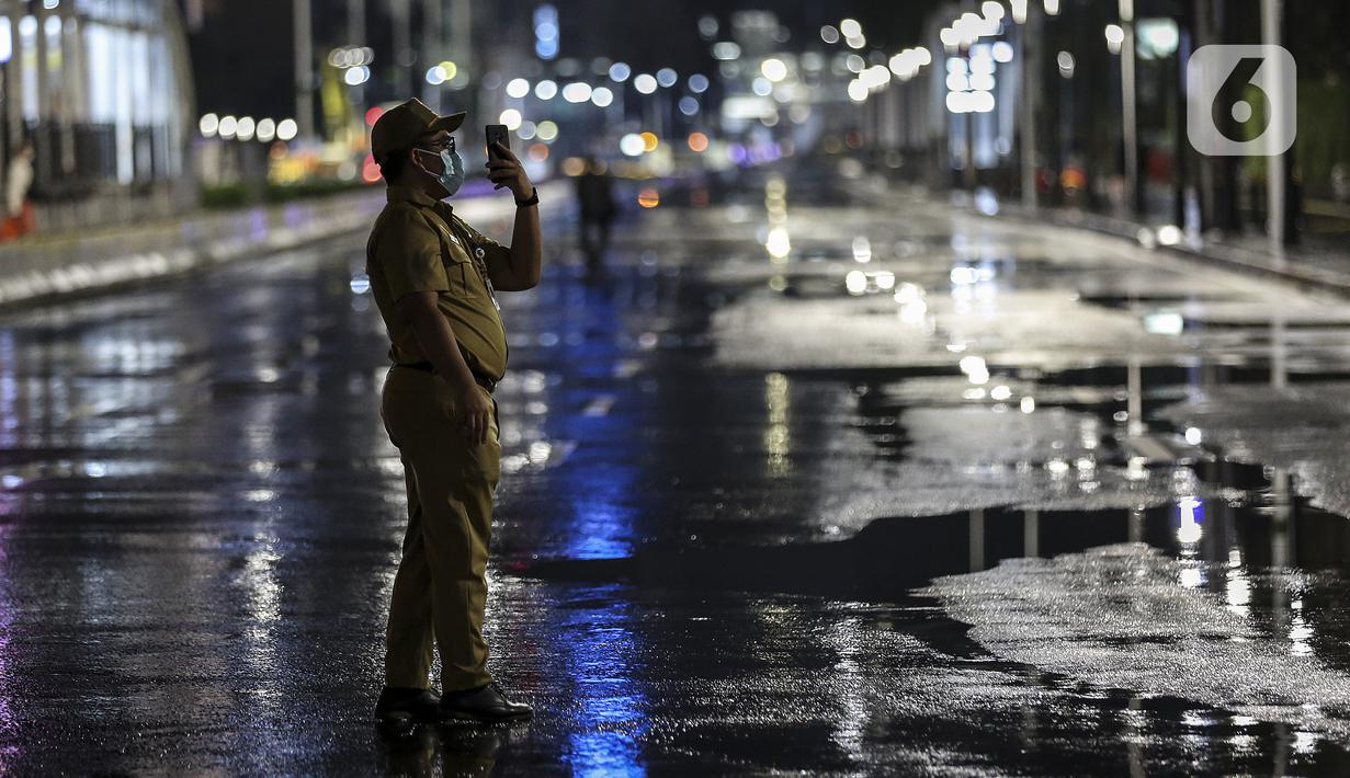 Seorang pria mengambil gambar saat diberlakukannya Car Free Night dan Crowd Free Night di Jalan Sudirman-MH Thamrin, Jakarta (31/12/2020). Jalan Sudirman-MH Thamrin ditutup pada malam pergantian tahun untuk mencegah kerumunan warga. (Liputan6.com/Johan Tallo)