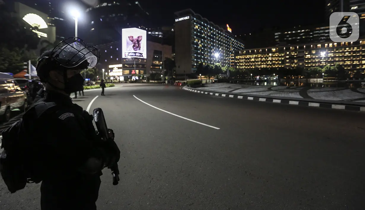 Petugas gabungan berjaga saat berlangsungnya Crowd Free Night di kawasan Bundaran HI, Jakarta, Jumat (31/12/2021). Polda Metro Jaya memberlakukan pengendalian mobilitas Crowd Free Night pada malam Tahun Baru 2022 yang berlangsung mulai pukul 22.00-04.00 WIB. (Liputan6.com/Johan Tallo)