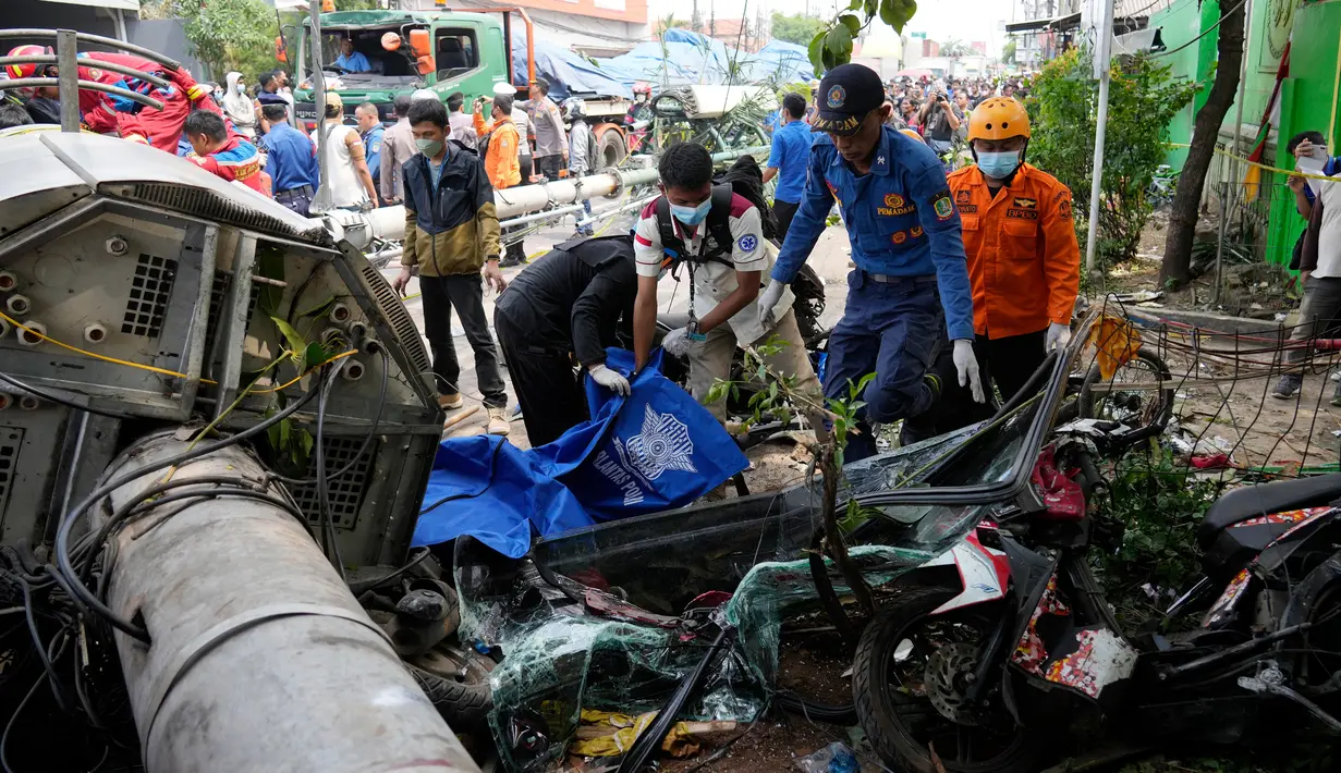 Polisi memasukkan jenazah korban ke dalam kantong jenazah usai kecelakaan lalu lintas di Bekasi, Indonesia, Rabu (31/8/2022). Kecelakaan memakan korban jiwa dan mengakibatkan sejumlah penguna jalan luka-luka. (AP Photo/Achmad Ibrahim)