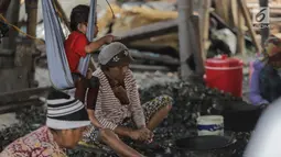 Seorang anak ikut menemani ibunya mengupas kerang hijau di Kampung Nelayan Muara Angke, Jakarta, Rabu (3/7/2019). Dengan penghasilan rata-rata Rp 30 ribu/hari, para buruh pengupas kerang hijau tersebut harus cukup memenuhi kebutuhan hidup keluarganya. (Liputan6.com/Faizal Fanani)