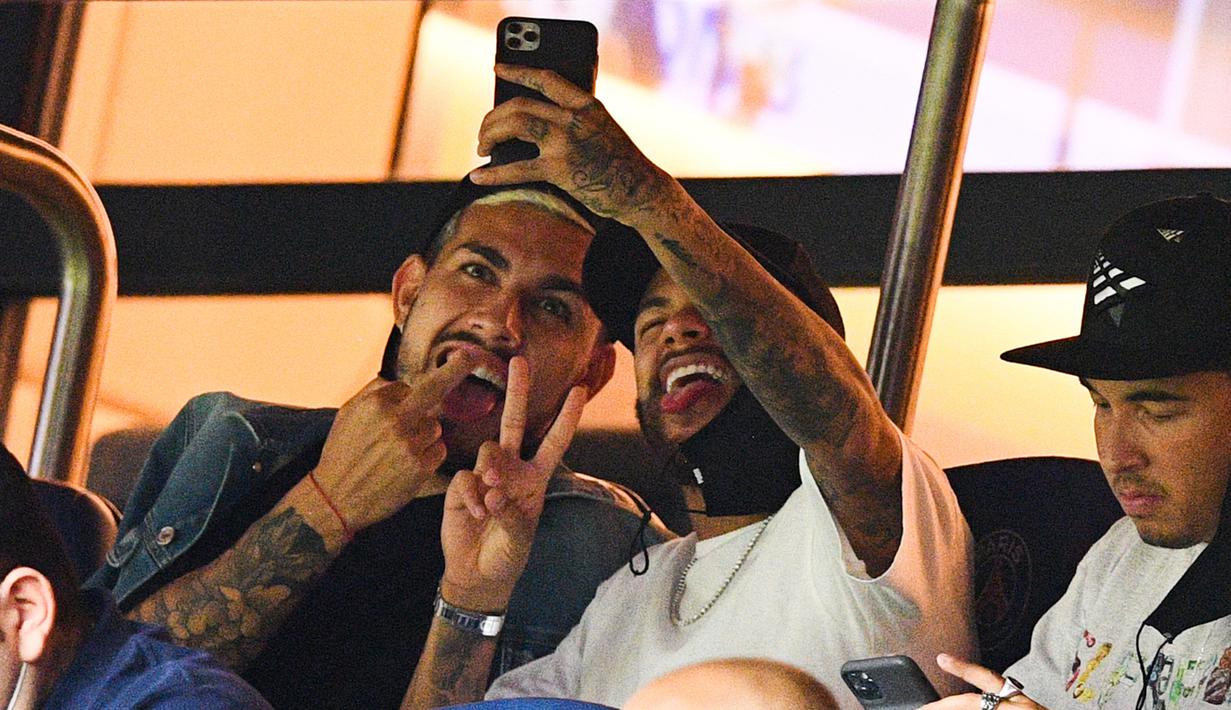 Pemain PSG, Neymar dan Leandro Paredes, melakukan swafoto saat menyaksikan pertandingan antara PSG melawan Metz pada laga Liga Prancis di Stadion Parc des Princes, Kamis (17/9/2020). Akibat pertikaian di laga melawan Marseille, Neymar dihukum larangan dua pertandingan. (AFP/Franck Fife)