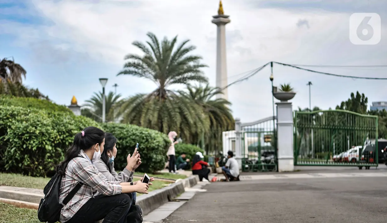 Warga menikmati sore hari di depan gerbang masuk Monumen Nasional (Monas), Jakarta, Minggu (15/11/2020). Meski masih ditutup untuk umum sejak awal pandemi Covid-19, kawasan Monas tetap ramai dikunjungi warga untuk sekadar mengisi akhir pekan. (merdeka.com/Iqbal S Nugroho)