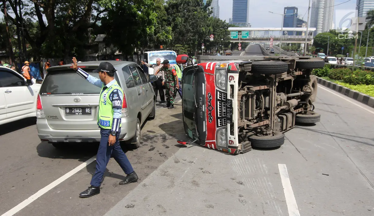 Petugas mengatur lalu lintas akibat mobil boks terguling di Jalan Casablanca, Jakarta, Rabu (27/6). Mobil bernomor polisi B 9515 FCC yang dikemudikan oleh Sumarno menabrak pembatas jalan. (Liputan6.com/Arya Manggala)