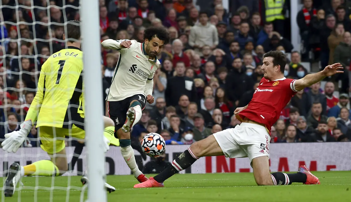 Pemain Liverpool Mohamed Salah mencoba melakukan tembakan ke gawang saat pemain Manchester United Harry Maguire (kanan) mencoba untuk memblokirnya pada pertandingan Liga Inggris di Old Trafford, Manchester, Inggris, Minggu (24/10/2021). Liverpool menang 5-0. (AP Photo/Rui Vieira)