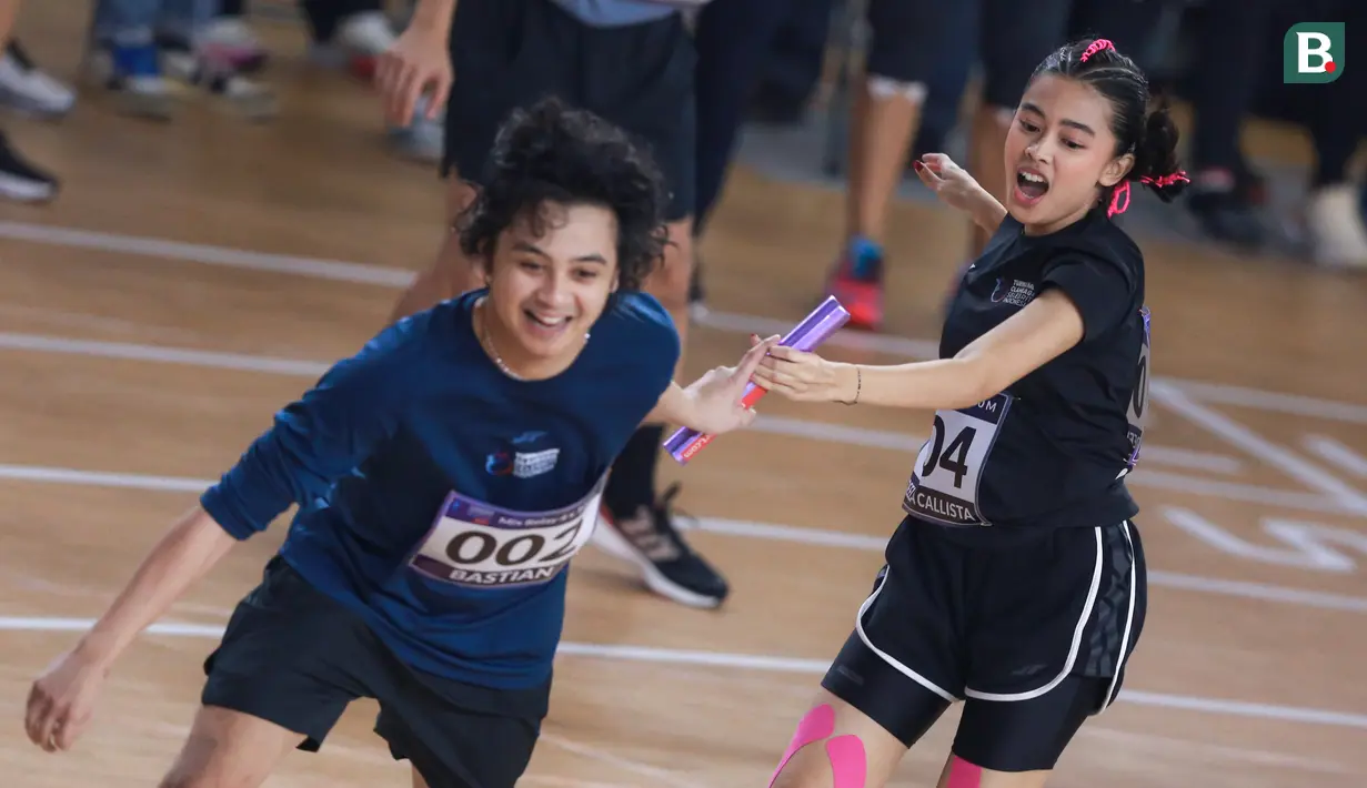 Selebritas Indonesia, Aqeela Calista (kanan) memberikan tongkat estafet kepada Bastian Steel saat berlomba pada cabang olahraga lari estafet 400 meter nomor campuran Turnamen Olahraga Selebriti Indonesia (TOSI) di GOR UNJ, Rawamangun, Jakarta, Minggu (30/07/2023). Mereka berhasil finis dengan catatan waktu 1 menit 0,59 detik. (Bola.com/Bagaskara Lazuardi)