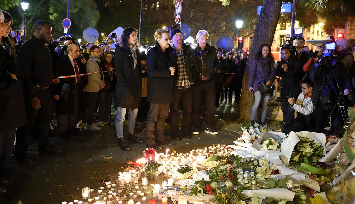 Grup band U2 Bono, Adam Clayton , Larry Mullen Jr  dan The Edge mengamati sejumlah karangan bunga di trotoar di depan gedung pertunjukan Bataclan Theatre, salah satu tempat serangan teroris di Paris, Perancis, Sabtu (14/11). (AFP PHOTO / FRANCK FIFE)