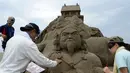 Seniman patung pasir berusaha menyelesaikan karya mereka yang diberi nama "Nihon Shoki" atau "The Chronicles of Japan" yang akan dipamerkan dalam Asahi Sand Sculpture di pantai Yasashigaura, Asahi, Chiba, (13/7/2014). (AFP PHOTO/Toshifumi Kitamura)