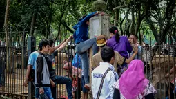 Sejumlah warga saat ingin memanjat pagar di kawasan monas, Jakarta, Minggu (19/4/2015). Aksi nekat Aksi nekat warga ini ditengarai oleh petugas yang menutup akses masuk pengunjung Monas di Kawasan pintu IRTI. (Liputan6.com/Faizal Fanani)