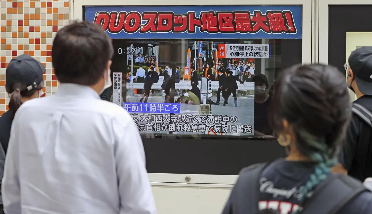 Orang-orang menonton berita TV yang melaporkan mantan Perdana Menteri Jepang Shinzo Abe ditembak, di Tokyo, Jumat (8/7/2022). Shinzo Abe yang berusia 67 tahun pingsan dan mengalami pendarahan di leher, kata seorang sumber dari Partai Demokrat Liberal yang berkuasa kepada kantor berita Jiji. (Kyodo News via AP)