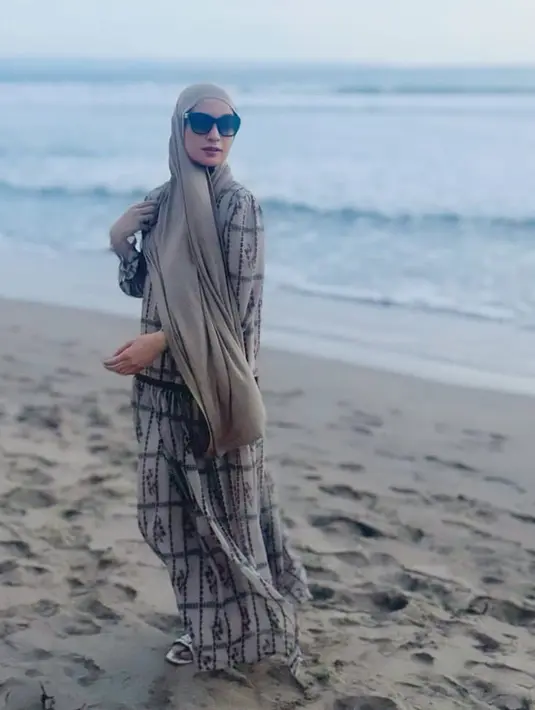 Shireen Sungkar juga liburan ke Bali bersama keluarga. Di pinggir pantai ia mengenakan dress panjang bermotif dipadukan pashmina coklat dan kacamata hitam. [@shireensungkar]