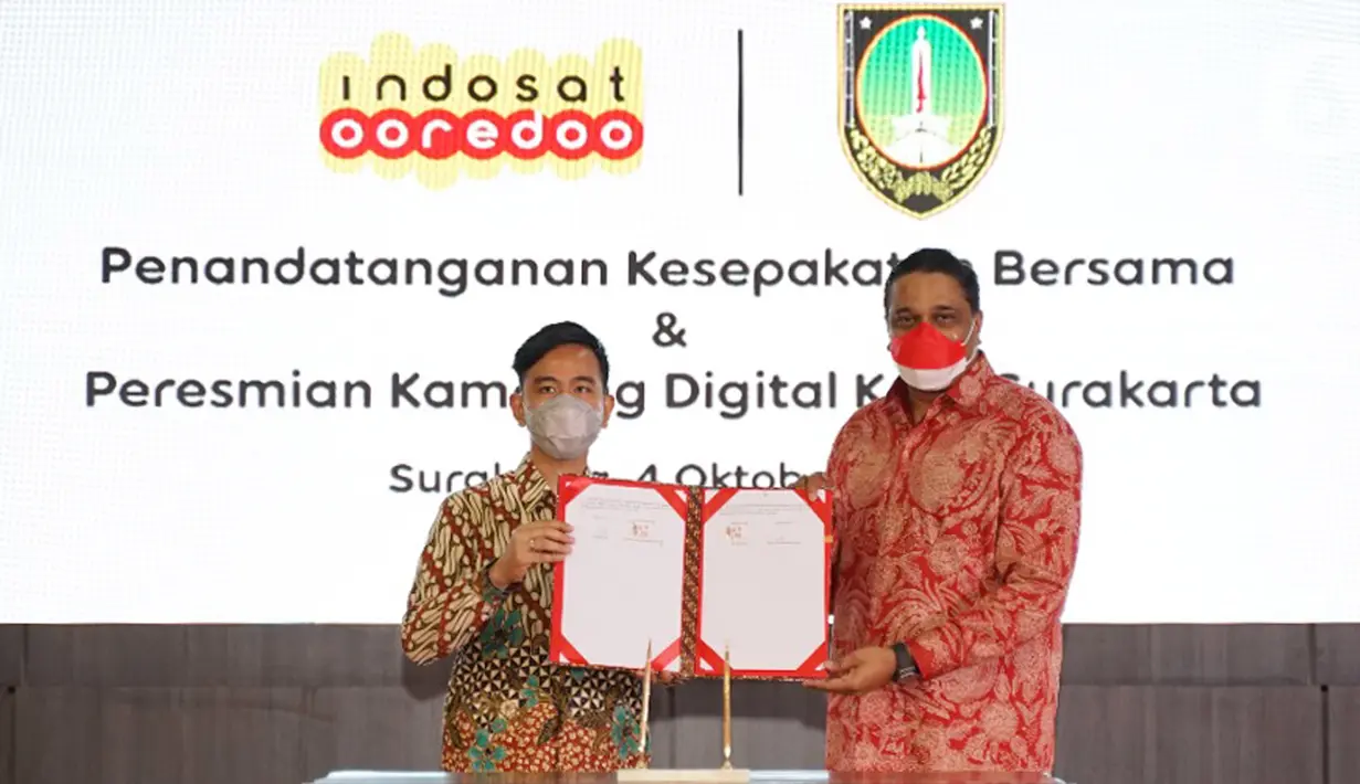 Wali Kota Solo Gibran Rakabuming Raka dan Director and COO Indosat Ooredoo Vikram Sinha menunjukkan penandatanganan kesepakatan kerja sama dukungan Indosat Ooredoo untuk pemulihan ekonomi Kota Solo dan peresmian kampung digital di Balai Kota Solo, Senin (4/10/2021). (Liputan6.com/HO/Indosat)