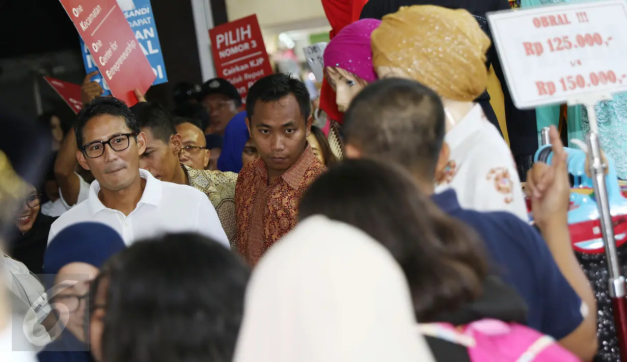 Cawagub DKI Jakarta, Sandiaga S Uno (kiri) berjalan menyusuri lorong pasar busana Blok A dan B Tanah Abang, Jakarta, Senin (26/12). Dihadapan para pedagang, Sandi mensosialisasikan beberapa program andalannya. (Liputan6.com/Helmi Fithriansyah)