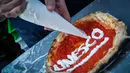 Koki menghias piza untuk merayakan penetapan seni memutar adonan piza masuk ke dalam "kebudayaan tak terlihat" milik UNESCO di Naples, Italia, 7 Desember 2017. Piza makanan asli benua Eropa yang lahir di kota Naples sekitar tahun 1720. (AP PHOTO)