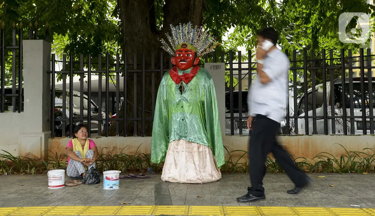 Pengamen ondel-ondel duduk di trotoar kawasan Sabang, Jakarta, Selasa (11/2/2020). DPRD DKI Jakarta berencana merevisi Perda Nomor 4 Tahun 2015 tentang Pelestarian Kebudayaan Betawi. Revisi ini bertujuan untuk melarang penggunaan ondel-ondel sebagai alat mengamen. (merdeka.com/Imam Buhori)