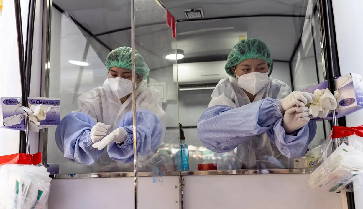 Petugas bersiap untuk mengambil sampel usap tenggorokan dan hidung dari dalam unit medis keliling saat uji virus corona COVID-19 bagi pekerja perhotelan dan pariwisata di Jalan Khao San, Bangkok, Thailand, Kamis (6/1/2022). (Jack TAYLOR/AFP)