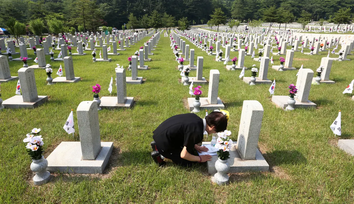 Warga Korea Selatan, Oh Myung-Soon menangis di depan batu nisan saudaranya yang meninggal selama Perang Korea di pemakaman nasional, Seoul, Korea Selatan, Rabu (6/6). Kegiatan ini dilakukan dalam Memorial Day. (AP Photo/Ahn Young-joon)