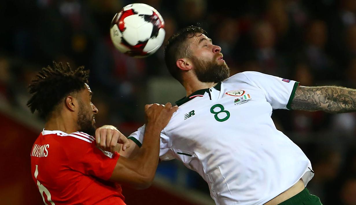 Striker Irlandia, Daryl Murphy, duel udara dengan bek Wales, Ashley Williams, pada laga kualifikasi Piala Dunia 2018 di Stadion Cardiff City, Cardiff, Senin (9/10/2017). Wales kalah 0-1 dari Irlandia. (AFP/Geoff Caddick)